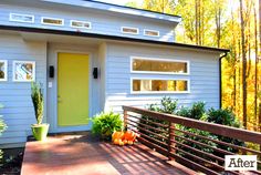 a small white house with yellow door and windows on the outside, surrounded by trees