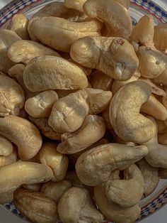 a bowl filled with cashews sitting on top of a white and blue checkered plate