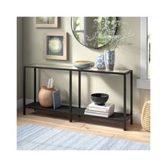 a black console table with books and vases on it in front of a mirror