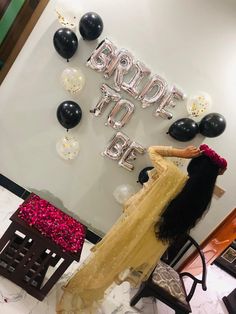 a woman in a yellow dress standing next to balloons and a sign that says bride to be