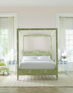 a white bed sitting in a bedroom next to two green chairs and lamps on either side of the bed