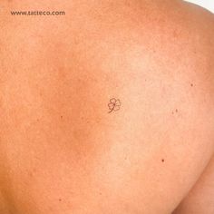 the back of a person's shoulder with a small tattoo on it