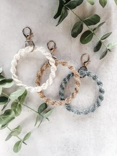 three different bracelets sitting on top of a table next to some plants and leaves