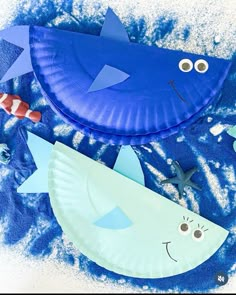 two paper plates with fish on them sitting in the snow next to some other items