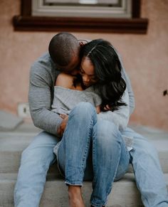 a man and woman sitting on the ground hugging each other with their arms around each other