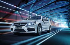 a white mercedes cla driving down a city street at night with motion blurs