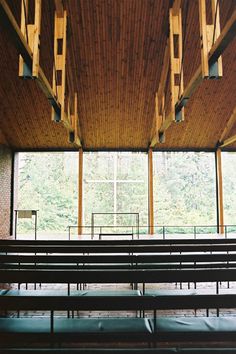 the inside of a church with rows of pews in front of large windows and wooden beams