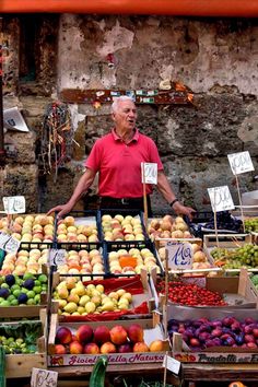 an older man standing in front of a fruit stand