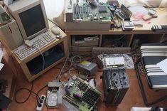 an assortment of electronic devices and equipment on a table in a cluttered office space