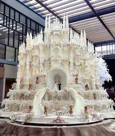 a large white cake with people standing in front of it