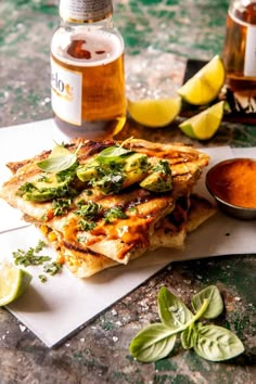 grilled sandwich with sauce and herbs on napkin next to jar of honey, lemon wedges and basil leaves