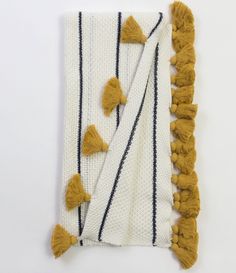 two pieces of fabric with tassels on them, one yellow and the other white