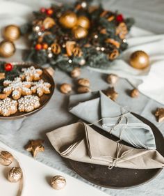 a table topped with cookies and other holiday decorations next to a plate of cookies on top of a cloth