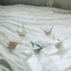 four origami cranes on a bed with white sheets