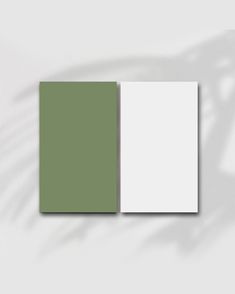 a green and white color palette with shadows on the wall, including two square pieces of paper