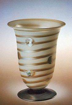 a white and brown striped glass vase sitting on top of a metal stand with holes in it