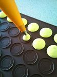 a person is making cupcakes with yellow icing on a baking tray and some black muffin tins