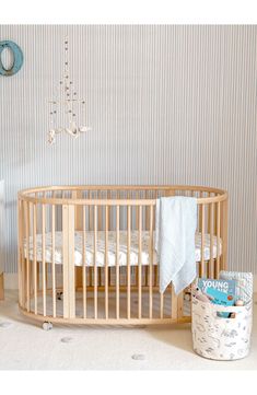 a baby crib next to a wallpapered wall in a room with blue and white striped walls