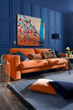 a living room with blue walls and orange couches in front of a painting on the wall