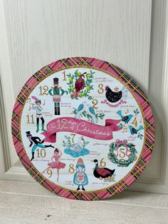 a clock with numbers and pictures on the front of it, decorated with pink ribbon