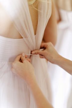 a woman in a white dress is trying on something