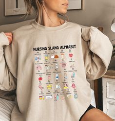 a woman is sitting on her bed wearing a sweatshirt with the words nursing sling alphabet