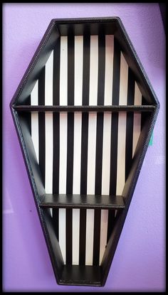 a black and white striped shelf on a purple wall