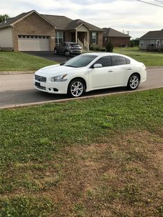 a white car is parked on the side of the road in front of some houses