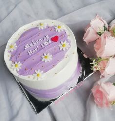 there is a cake with flowers on the table next to it and two pink roses