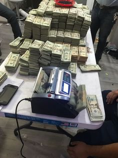 stacks of money sitting on top of a table next to a cell phone and other electronic devices