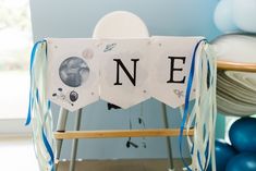 a wooden chair decorated with blue balloons and paper signs that spell out the word ne