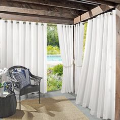 a living room filled with furniture and white drapes on the window sill next to an outdoor swimming pool