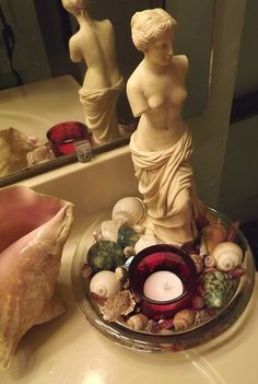 there is a candle and some shells on the sink