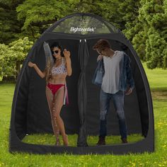 a man and woman standing in front of a black tent