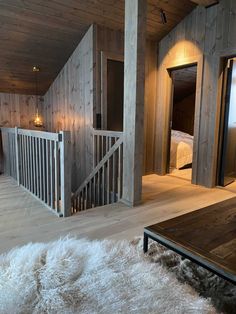 a living room with wooden walls and white fur rugs on the floor next to stairs