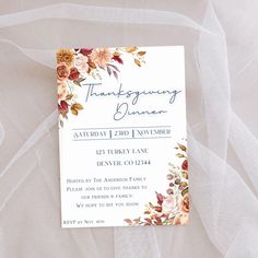 a wedding card with flowers on it sitting on top of a white cloth covered table