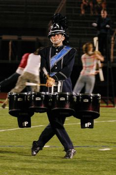 a man in uniform is playing drums on the field