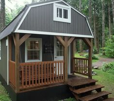 a small house with stairs leading to the front door and covered porch in the woods