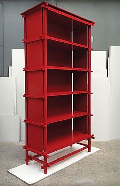 a red bookcase sitting on top of a white platform