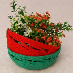 a green and red basket with flowers in it