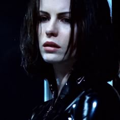 a woman with dark hair and black latex is staring at something in the distance