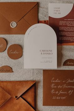 the wedding stationery is laid out on top of brown envelopes and matching paper