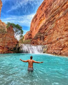 a man standing in the middle of a body of water with his arms spread out