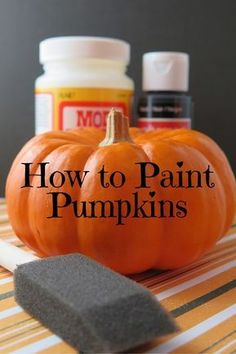 an orange pumpkin sitting on top of a table next to some paint and a sponge