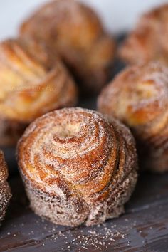 several pastries sitting on top of a wooden table covered in powdered sugar and sprinkles