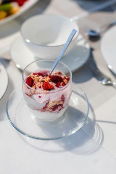 a bowl of yogurt with strawberries and granola in it on a plate