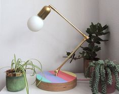 a desk lamp sitting on top of a white table next to a potted plant