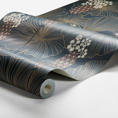 a roll of blue and gold wallpaper with large flowers on the side, next to a roll of tape