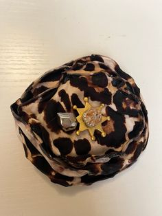 a brown and black animal print hat with a gold star brooch