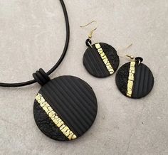 two black and gold necklaces on a white surface with a black cord attached to it